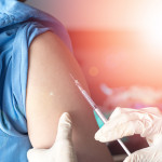 Vaccination healthcare concept. Hands of doctor or nurse in medical gloves injecting a shot of vaccine to a man patient.