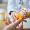 pharmacist hands bottle of pills to customer