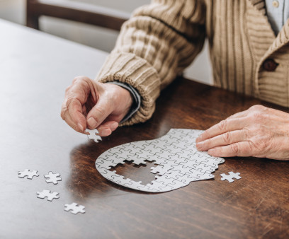 mans hands putting together puzzle pieces to make a head