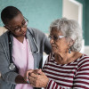 Black nurse comforts older woman