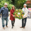 Speaker Emerita Nancy Pelosi displays the Grove Volunteer Workday Commemorative Wreath along with John Cunningham, CEO, National AIDS Memorial on the right, and Mike Shriver, former National AIDS Memorial board member and AIDS Activist, on the left.
