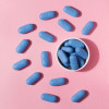 blue pills in a cup and on a pink background