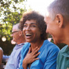 a group of adults sitting in the park laughing