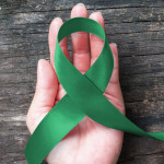 hand with green ribbon cerebral palsy and liver cancer awareness