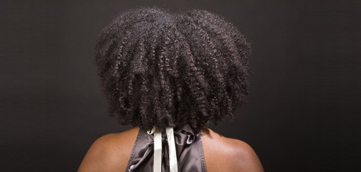 the back of an African American woman's head showing her curly afro and bare shoulders
